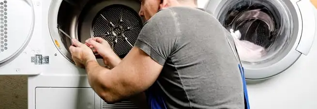 Dryer repair technician fixing a clothes dryer drum in Columbia, MO