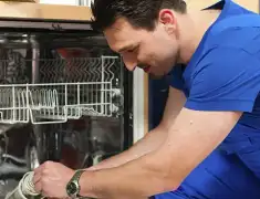 Dishwasher repair technician inspecting and servicing an open dishwasher in Columbia, MO