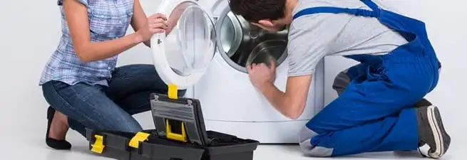 Washer repair technician inspecting a front-load washing machine with tools in Columbia, MO
