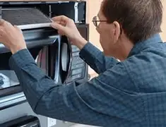 Appliance repair technician replacing a microwave vent filter in Columbia, MO