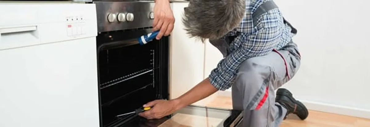 Oven repair technician inspecting and servicing an electric oven in Columbia, MO