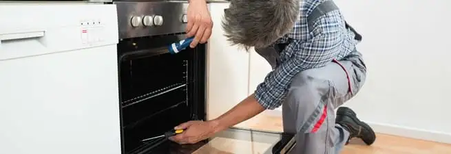 Oven repair technician inspecting and servicing an electric oven in Columbia, MO