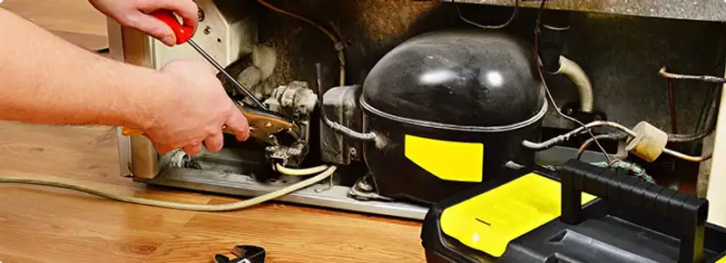 Refrigerator repair technician fixing the compressor and wiring in Columbia, MO