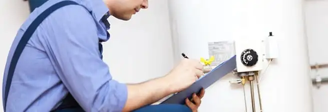 Water heater repair technician inspecting the unit and recording service notes in Columbia, MO